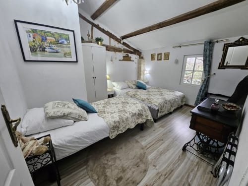 Geräumiges Schlafzimmer mit Einzelbetten, sichtbaren Holzbalken, weißen Wänden und Gartenblick im Manoir Lacustre, Queyrac.