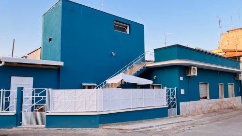 Esterno della struttura Bari Vacation BnB a Cienfuegos, Italia. Edificio moderno blu con cancello bianco e area terrazza.
