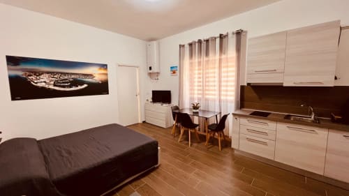 Monolocale moderno a Bari con letto, angolo cottura, zona pranzo e vista sulla città dalle finestre a righe