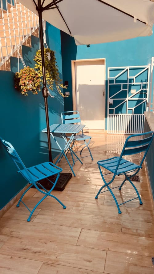 Patio azzurro caraibico dell'appartamento vacanze a Bari con sedie blu, ombrellone e piante sospese