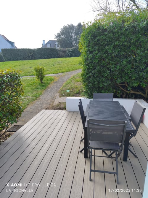 Terrasse de dining extérieure de l'appartement Locmaria avec vue sur le jardin, terrasse composite grise et mobilier noir