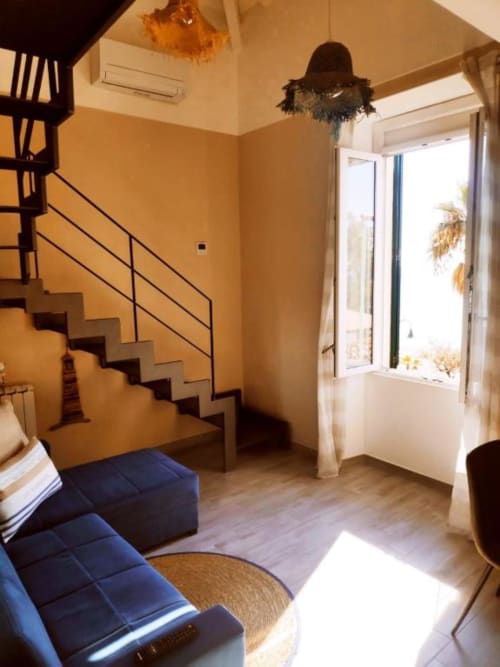 Luminoso appartamento moderno a Ventimiglia con scale, divano blu, parquet e affaccio sul mare