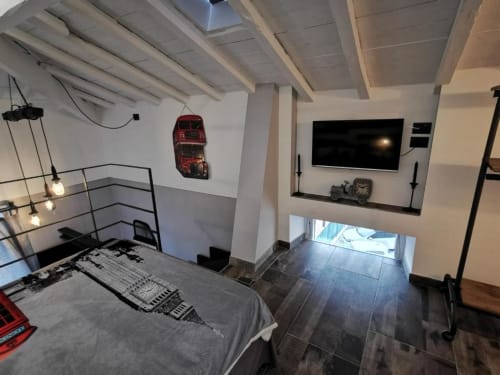 Camera moderna dell'appartamento TuffonelBlu a Ventimiglia con TV, letto, travi a vista, decorazione auto rossa e finestra con vista mare