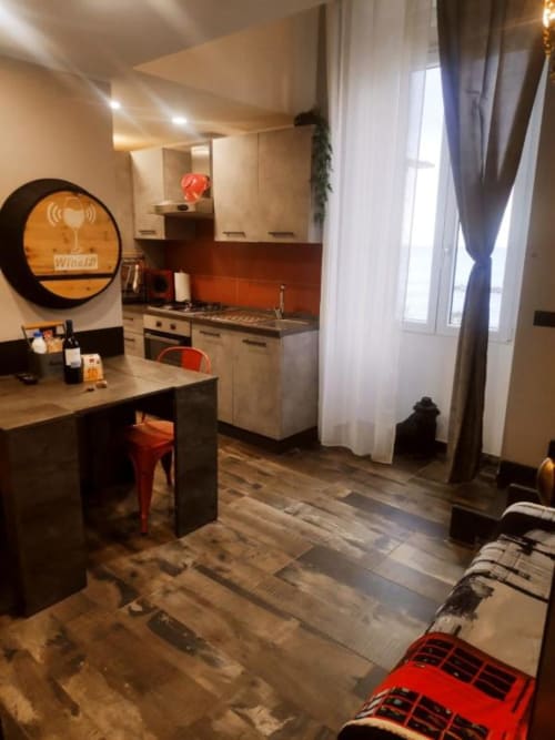 Cucina moderna e zona living nell'appartamento TuffonelBlu a Ventimiglia, con angolo cottura, tavolo da pranzo e finestre con vista mare