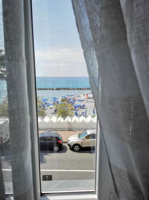 Vista sul mare dall'appartamento TuffonelBlu a Ventimiglia, con spiaggia, ombrelloni blu e Mar Mediterraneo
