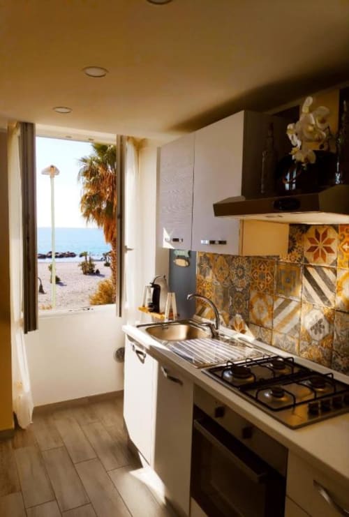 Cucina moderna con vista mare nell'appartamento TuffonelBlu, Ventimiglia. Fornello a gas, lavello, piastrelle decorate, accesso alla spiaggia.