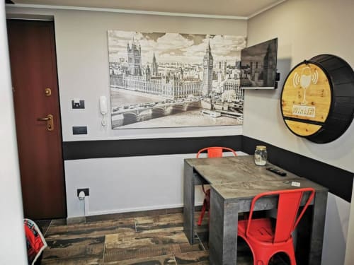 Moderno spazio di lavoro in appartamento a Ventimiglia con scrivania, sedie rosse e decorazione murale con skyline di Londra
