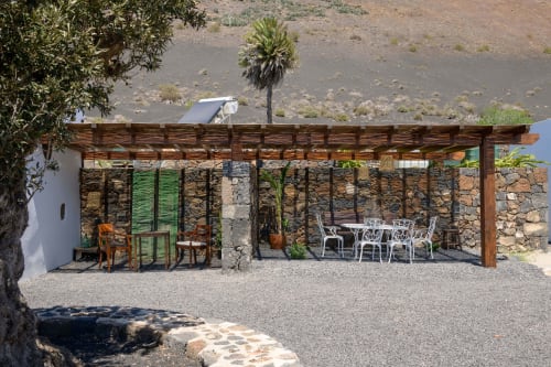 Finca de La Geria pergola terrace with stone walls, dining furniture, and volcanic landscape in Yaiza
