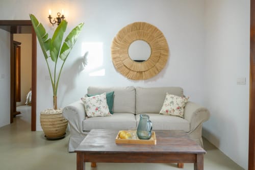 Elegant living room at Finca de La Geria with beige sofa, woven mirror, and tropical plants in Yaiza