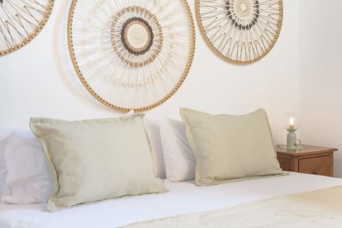 Minimalist bedroom at Finca de La Geria in Yaiza with cream pillows, woven wall art, and wooden nightstand lamp.