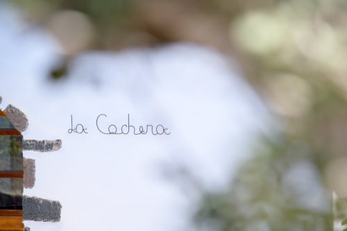 La Cochera sign at Finca de La Geria hotel in Yaiza with blurred white building background