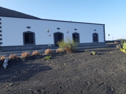 Finca de La Geria hotel exterior with white walls, dark doors, and volcanic landscape in Yaiza