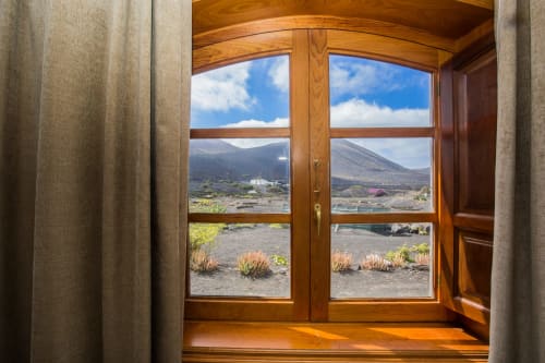 Wooden window frame at Finca de La Geria with volcanic landscape and mountains visible through glass panes in Yaiza