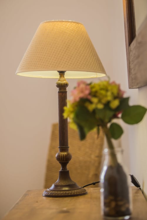 Elegante lámpara de mesa con pantalla color crema y base decorativa de bronce en el hotel Finca de La Gería en Yaiza
