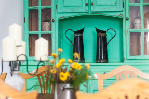 Mueble turquesa con jarras negras en Finca de La Geria, Yaiza, decoración rústica de hospitalidad con flores amarillas