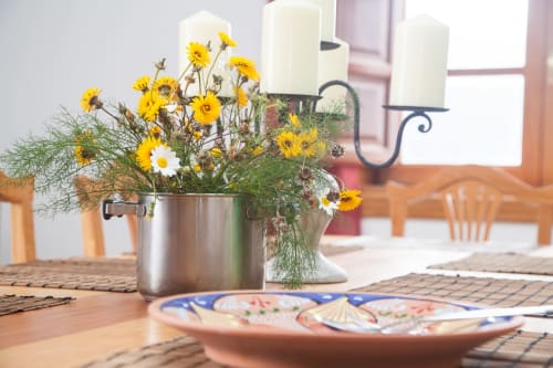 Margaritas amarillo brillante en maceta de metal sobre mesa de comedor de madera en Finca de La Geria, Yaiza