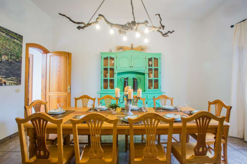 Dining room at Finca de La Geria with wooden table, turquoise cabinet, and rustic branch chandelier