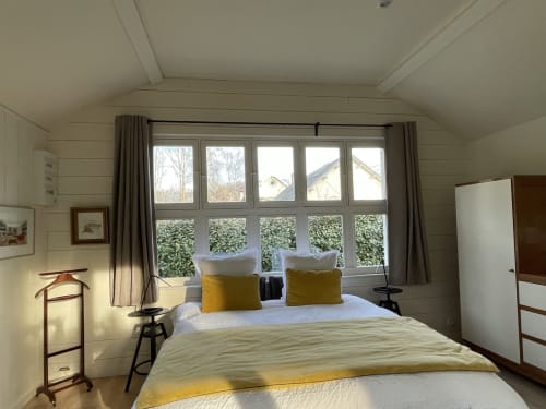 Bright bedroom in The Lanterne cottage at Clairseine B&B with garden views, yellow accents, and large windows overlooking