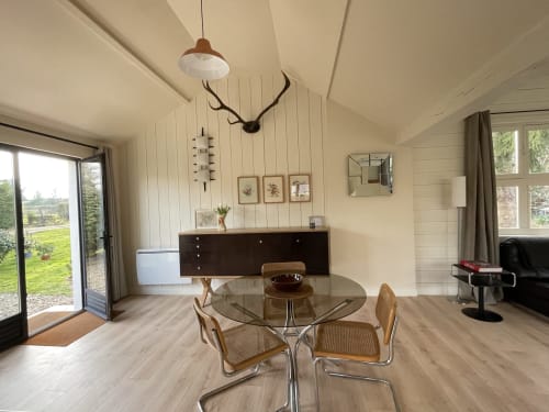 Modern cottage dining area at Clairseine B&B with round glass table, mid-century chairs, and garden views in
