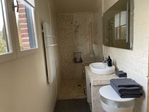 Modern bathroom in Clairseine cottage with walk-in shower, dual sinks, and dark towels at Tournedos-sur-Seine