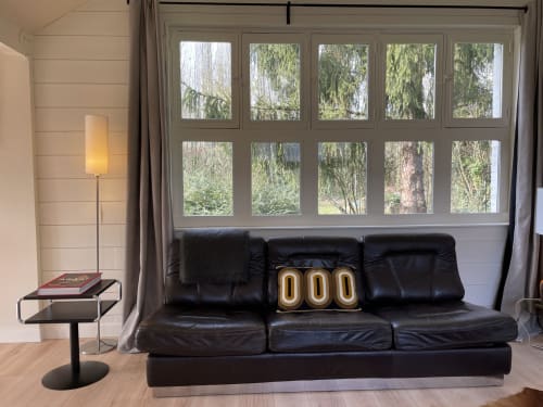 Modern black leather sofa in The Lanterne cottage at Clairseine B&B, with garden view windows and minimalist décor