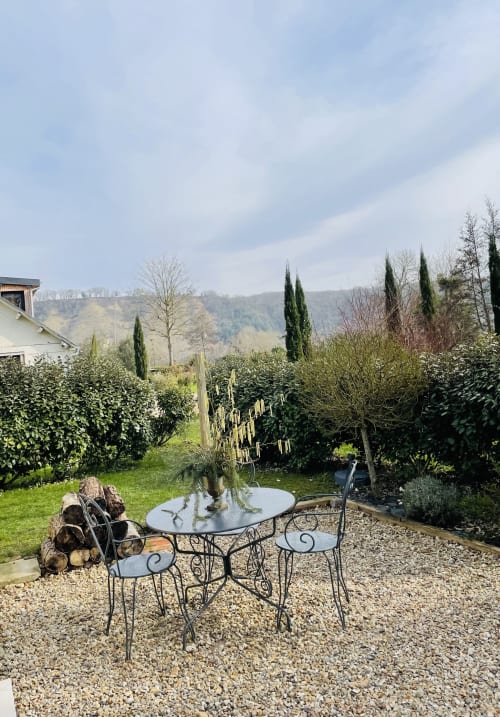 Seating area on gravel terrace at Clairseine cottage in Tournedos-sur-Seine with garden view and hillside backdrop
