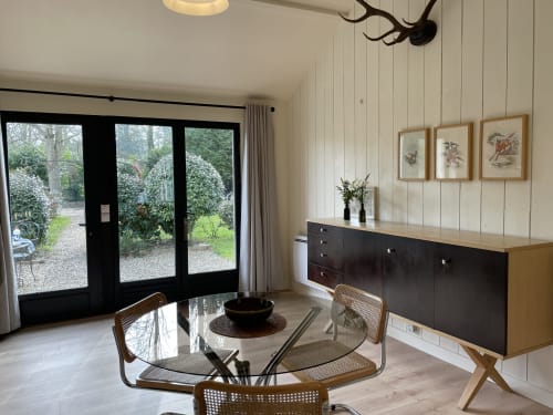 Modern dining room in The Lanterne cottage at Clairseine BnB with garden views through black glass doors, round table with