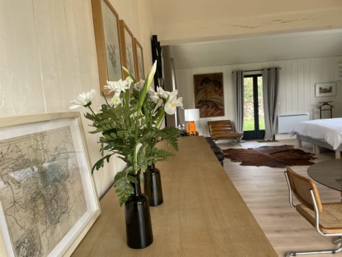 White flowers in black vase on wooden desk in The Lanterne cottage at Clairseine BnB, Tournedos-sur-Seine