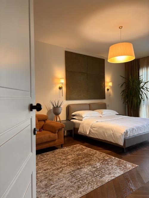 Camera moderna del B&B Delta Majestic a Pordenone con letto matrimoniale, poltrona in terracotta, lampada a sospensione e atmosfera calda