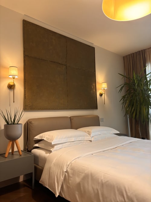 Camera moderna della B&B Delta Majestic a Pordenone con biancheria bianca, testata in bronzo e illuminazione calda