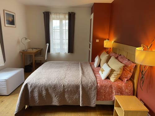 Chambre accueillante à la maison d'hôtes Entre Terre Et Ciel à Rémuzat avec lit queen-size, bureau et mur d'accent orange chaleureux