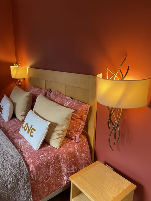 Chambre chaleureusement éclairée à Entre Terre Et Ciel avec lit à tête de lit en bois, parure de lit bordeaux et coussins décoratifs