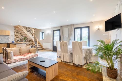 Helles offenes Wohnzimmer im Gîte Le Penty in Concarneau mit Steintreppe, cremefarbenen Möbeln, TV, Pflanzen und