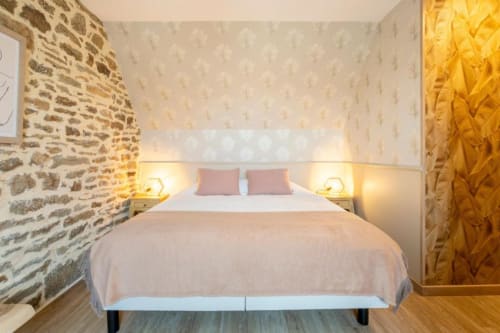 Modernes Cottage-Schlafzimmer mit Steinmauer, rosa Kissen und warmer Beleuchtung in Les logis de Kergoulou, Concarneau