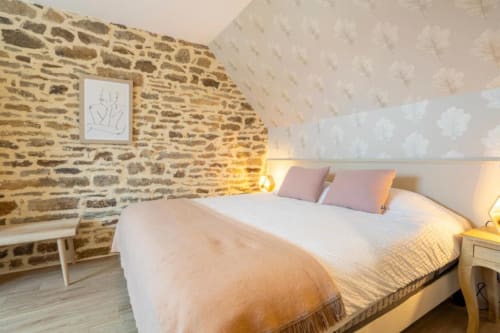 Gemütliches Dachzimmer im Ferienhaus Les Logis de Korgoulou in Concarneau mit sichtbarem Naturstein, weißer Bettwäsche und warmem Licht