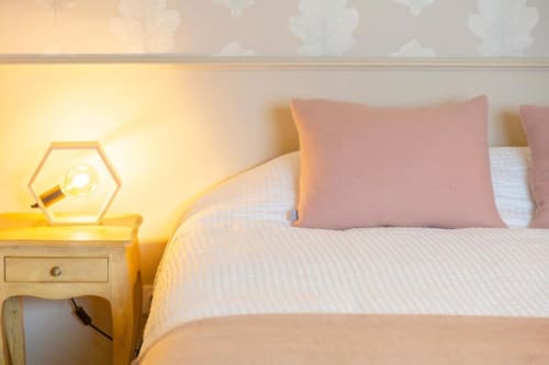 Gemütliches Schlafzimmer im Cottage Les logis de Kergoulou in Concarneau mit rosa Kissen, warmer sechseckiger Lampe und Gartenblick