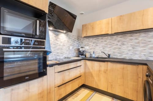 Moderne Küche mit Holzschränken, schwarzen Arbeitsplatten und Marmor-Spritzschutz im Gîte Le Penty in Concarneau