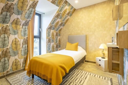 Helles Schlafzimmer mit gelben Wänden, Blattmuster-Tapete und Gartenblick im Ferienhaus Les logis de Kergoulou, Concarneau