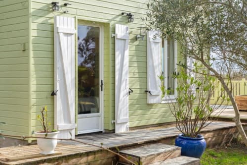 Charmant cottage vert aux Logis de Kergoulou avec volets blancs, porte vitrée, terrasse bois et jardin
