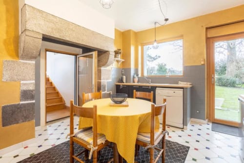 Bright yellow dining room with round table, wooden chairs, and garden view in Gîte Le Studio Terrasse cottage at Les logis de