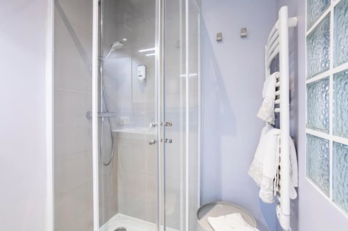 Modern shared bathroom with shower cubicle, towel rack, and white fixtures at Les logis de Kergoulou cottage in Concarneau