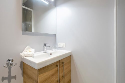 Modern bathroom with wooden vanity, white sink, and mirror in Gîte Le Studio Terrasse at Les logis de Kergoulou, Concarneau