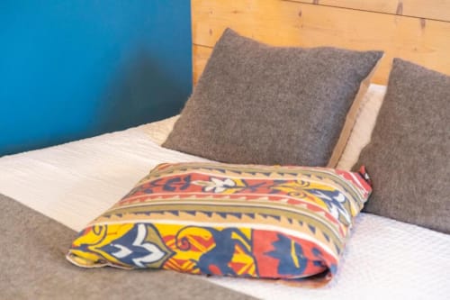 Colorful decorative pillow on white bedding with gray cushions in a cottage bedroom at Les logis de Kergoulou, Concarneau