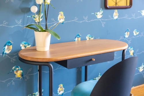 Wooden desk with white flower pot against blue bird-patterned wall in Madame de la Fayette room at Les logis de Kergoulou,