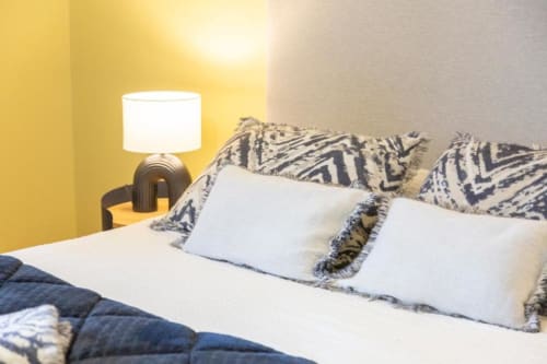 Cozy bedroom at Les logis de Kergoulou in Concarneau with white pillows, patterned headboard, and warm table lamp.