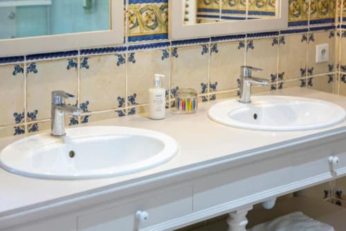 Shared bathroom with dual sinks, decorative blue tile backsplash, and chrome fixtures at Les logis de Kergoulou B&B in