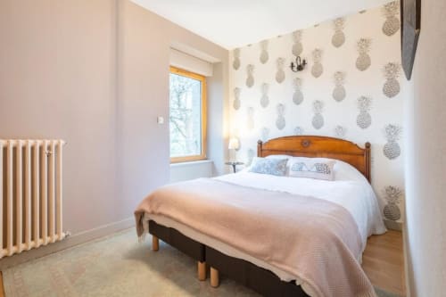 Cozy bedroom in Les logis de Kergoulou B&B, Concarneau, with pineapple-patterned wallpaper and wooden bed