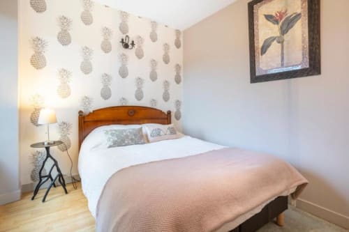 Cozy bedroom at Les logis de Kergoulou in Concarneau with pineapple wallpaper, wooden bed, and garden view