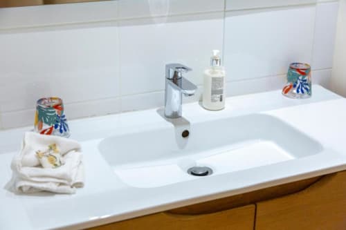 Modern bathroom vanity with dual sink, soap dispenser, and decorative towels at Les logis de Kergoulou B&B in Concarneau