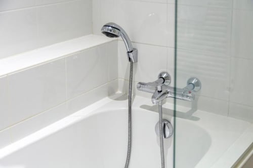 Modern shower with handheld showerhead and wall-mounted controls in Anne de Bretagne suite at Les logis de Kergoulou,